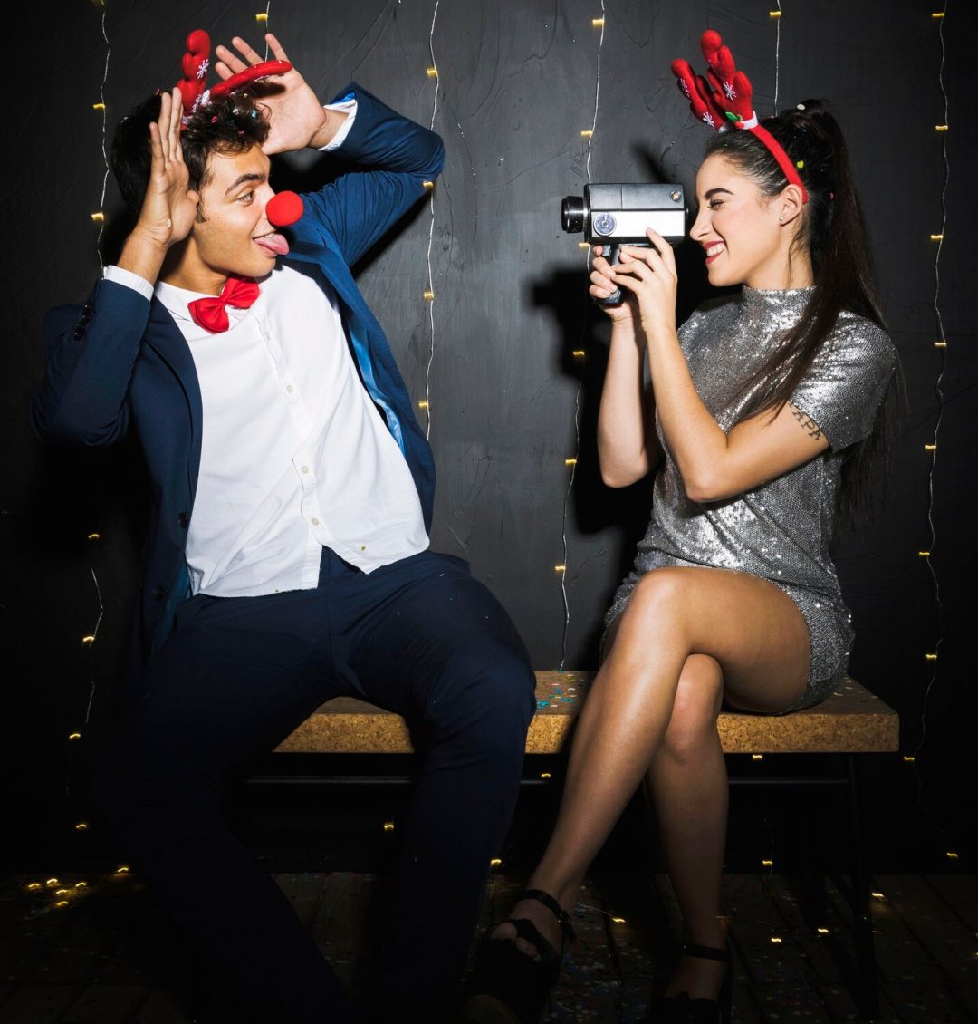 couple-with-deer-antlers-headbands-funny-noses-capturing-video_23-2147972098